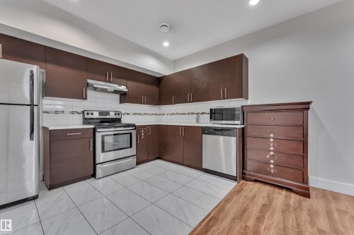 Kitchen featuring dark wood cabinetry, white countertops, stainless steel appliances, and white tile flooring - 3001 55 Street, Beaumont, AB - Indoor Photo Showing Kitchen