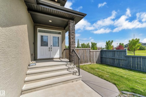 Double white entry doors with decorative glass inserts, sheltered by an overhang with a recessed light fixture - 3001 55 Street, Beaumont, AB - Outdoor