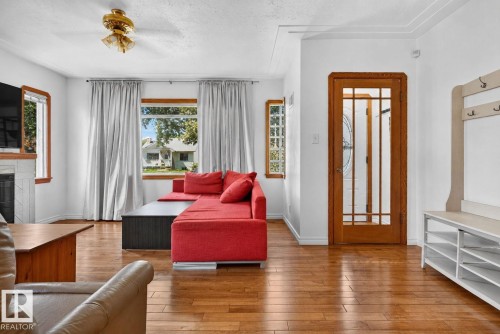 Bright interior space featuring wood-finish flooring, white walls, and a ceiling fan - 12229 88 Street Nw, Edmonton, AB - Indoor Photo Showing Living Room With Fireplace