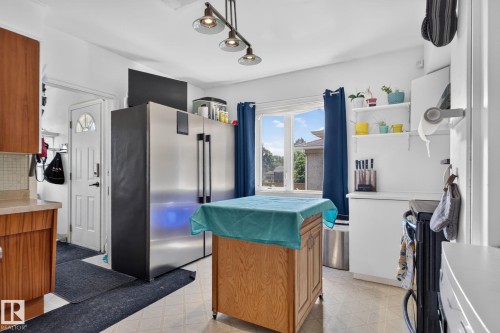 Kitchen featuring a large window, track lighting, wood-finish cabinetry, and white countertops - 12229 88 Street Nw, Edmonton, AB - Indoor Photo Showing Kitchen