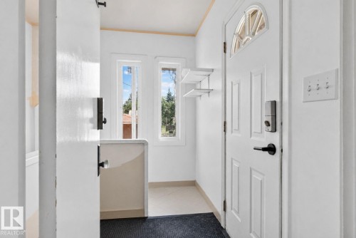 Entryway featuring a paneled door with an arched window, a digital lock, and a matte black handle - 12229 88 Street Nw, Edmonton, AB - Indoor Photo Showing Other Room