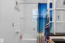 Bathroom featuring a white subway tile surround, a built-in bathtub, a window with obscure glass, and an integrated storage unit - 