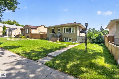Single-story residence featuring a neutral exterior, concrete walkway, and an expansive front lawn - 12229 88 Street Nw, Edmonton, AB - Outdoor