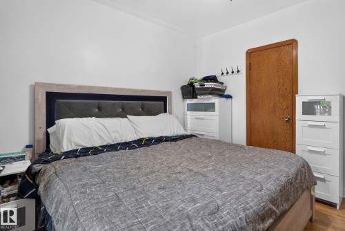 White walls with crown molding, wood-finish flooring, and a textured solid core door - 12229 88 Street Nw, Edmonton, AB - Indoor Photo Showing Bedroom