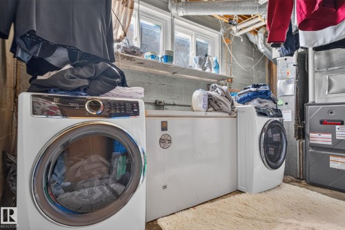 Dedicated laundry area featuring a front-loading washer and dryer, a utility sink, and built-in shelving - 12229 88 Street Nw, Edmonton, AB - Indoor Photo Showing Laundry Room