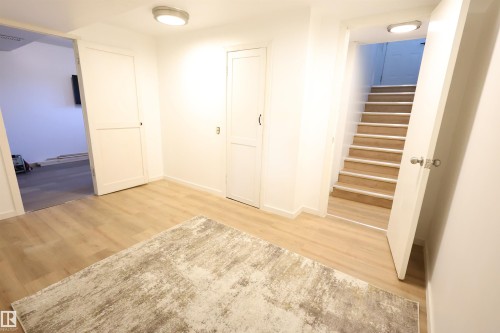Wood-finish flooring, recessed lighting, white panel doors, and a wood-finish staircase - 12229 88 Street Nw, Edmonton, AB - Indoor Photo Showing Other Room