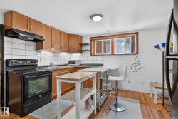 Kitchen featuring wood-finish flooring, wood cabinetry, white tile backsplash, and a black electric range - 