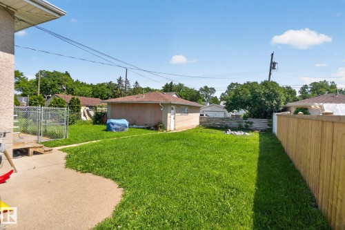 Expansive backyard featuring a concrete patio, lush green lawn, wood fence, and detached garage - 12229 88 Street Nw, Edmonton, AB - Outdoor