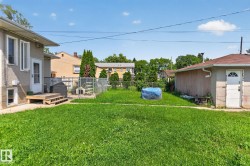 Expansive grassy yard area with a stucco-finish house exterior and a detached garage featuring an arched window door - 