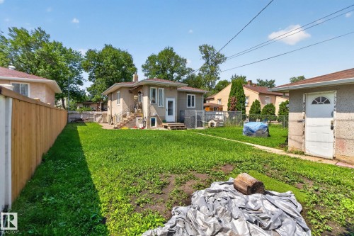 Expansive backyard featuring a manicured lawn, a detached garage, and a wooden privacy fence - 12229 88 Street Nw, Edmonton, AB - Outdoor