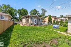 Expansive rear yard featuring a paved walkway, a wood privacy fence, and mature trees - 