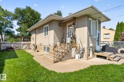 Stucco exterior home featuring a concrete patio, exterior stairs with metal railings, and a side-yard access - 