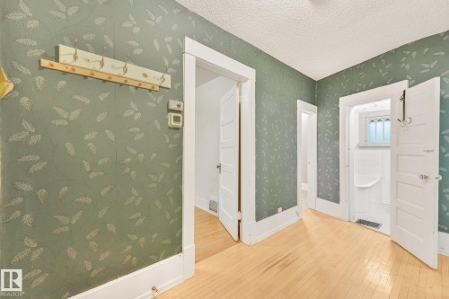 Hardwood flooring complemented by patterned wall coverings - 9824 91 Avenue Nw, Edmonton, AB - Indoor Photo Showing Other Room