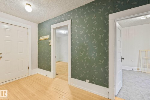 Hardwood flooring in a natural finish, white paneled doors, and a decorative wall covering - 9824 91 Avenue Nw, Edmonton, AB - Indoor Photo Showing Other Room