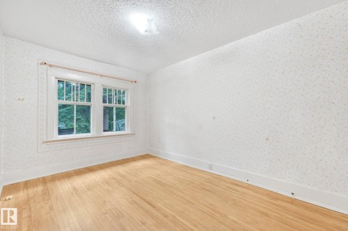 Room featuring wood-finish flooring, a double window with white trim, a textured ceiling, and a flush-mount light fixture - 9824 91 Avenue Nw, Edmonton, AB - Indoor Photo Showing Other Room