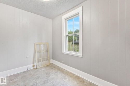 Room featuring light-colored wall paneling, a single-hung window with white trim, and a textured ceiling - 9824 91 Avenue Nw, Edmonton, AB - Indoor Photo Showing Other Room