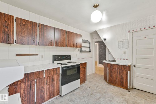 Kitchen featuring wood-grain cabinetry, white tile backsplash, a built-in range, and a white countertop - 9824 91 Avenue Nw, Edmonton, AB - Indoor Photo Showing Kitchen