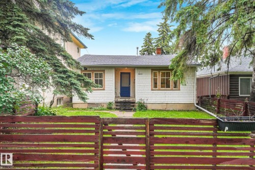 Cottage-style home featuring light-colored shingle siding and a dark blue entry door - 9824 91 Avenue Nw, Edmonton, AB - Outdoor