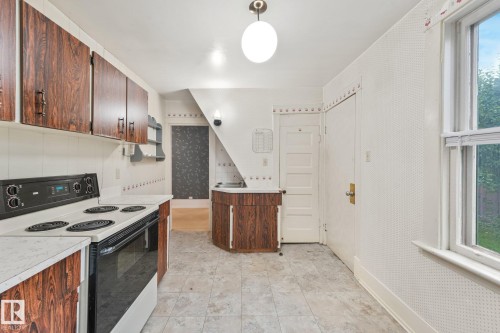 Kitchen featuring wood-finish cabinetry, a black electric range, a wall-mounted sink, and a multi-pane window - 9824 91 Avenue Nw, Edmonton, AB - Indoor Photo Showing Kitchen