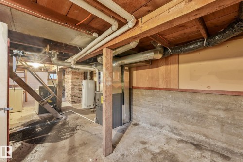 Unfinished basement featuring exposed wood joists, concrete foundation walls, and various utility systems including plumbing, ductwork, and a water heater - 9824 91 Avenue Nw, Edmonton, AB - Indoor Photo Showing Basement