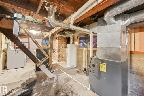 Utility area featuring a furnace system, water heater, and exposed brick wall - 9824 91 Avenue Nw, Edmonton, AB - Indoor Photo Showing Basement