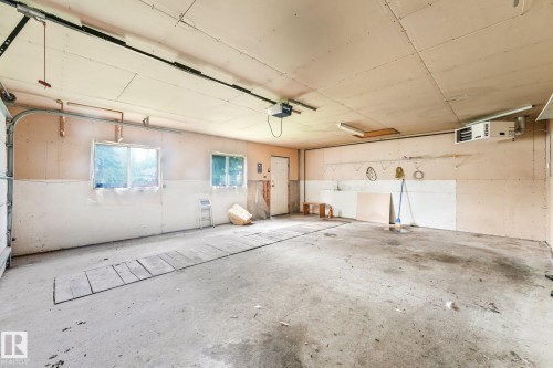 Spacious garage featuring concrete flooring, multiple windows providing natural light, exposed ceiling beams, and overhead fluorescent lighting - 9824 91 Avenue Nw, Edmonton, AB - Indoor Photo Showing Garage