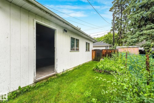 White vertical siding building with an open doorway, multiple windows, and a green grass perimeter - 9824 91 Avenue Nw, Edmonton, AB - Outdoor