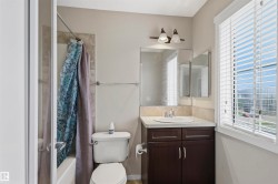 Bathroom featuring a white vanity with a dark wood-finish cabinet, a white ceramic sink, and a chrome faucet - 