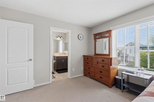 Bedroom featuring light grey walls, carpet flooring, a white paneled door, and a window with blinds - 1528 35 Avenue Nw, Edmonton, AB - Indoor