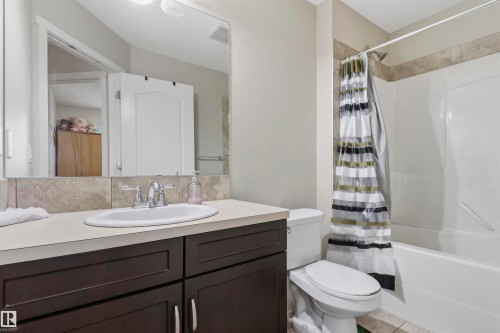 Bathroom featuring a dark wood-finish vanity with a light-toned countertop, an undermount sink, and a chrome faucet - 1528 35 Avenue Nw, Edmonton, AB - Indoor Photo Showing Bathroom