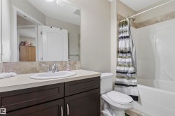 Bathroom featuring a dark wood-finish vanity with a light-toned countertop, an undermount sink, and a chrome faucet - 