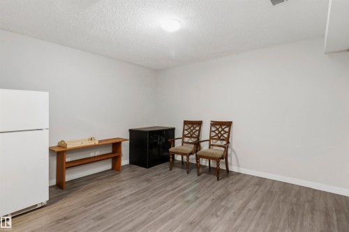 Spacious room featuring light gray walls, wood-finish flooring, and white baseboards - 1528 35 Avenue Nw, Edmonton, AB - Indoor Photo Showing Other Room