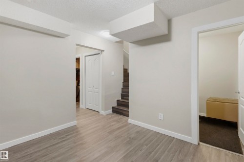 Open living area featuring light gray walls, white trim, and wood-finish flooring - 1528 35 Avenue Nw, Edmonton, AB - Indoor Photo Showing Other Room
