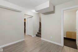 Open living area featuring light gray walls, white trim, and wood-finish flooring - 