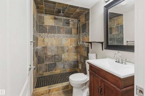 Full tile shower surround with a mosaic accent band, integrated showerhead, and handheld shower sprayer - 1528 35 Avenue Nw, Edmonton, AB - Indoor Photo Showing Bathroom