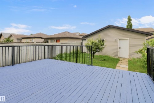 Spacious outdoor deck with painted wood planks and black metal railing, offering direct access to a separate detached structure with siding exterior and a concrete pathway - 1528 35 Avenue Nw, Edmonton, AB - Outdoor With Deck Patio Veranda With Exterior