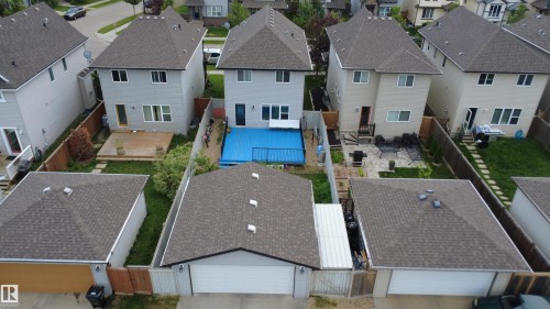 Rear exterior featuring a blue-covered backyard pool, a wooden deck, and a detached two-car garage with an asphalt shingle roof - 1528 35 Avenue Nw, Edmonton, AB - Outdoor