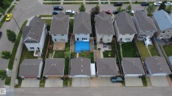 Rear yard featuring a blue-lined pool with surrounding deck, adjacent to a structured patio area - 