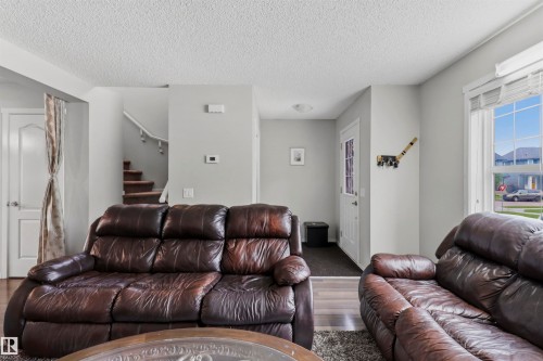 Living area featuring light gray wall paint, textured ceiling, a window with horizontal blinds, and dark-toned flooring - 1528 35 Avenue Nw, Edmonton, AB - Indoor Photo Showing Living Room