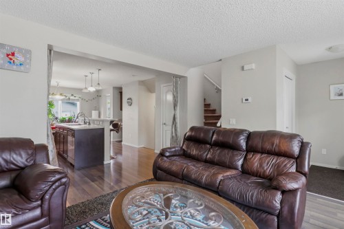 Open-concept living area featuring rich wood-finish flooring, a kitchen island with pendant lighting, and a staircase with a wooden handrail - 1528 35 Avenue Nw, Edmonton, AB - Indoor Photo Showing Living Room