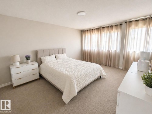 Neutral color palette with broadloom carpeting and a horizontal paneled headboard - 1327 20 Nw, Edmonton, AB - Indoor Photo Showing Bedroom