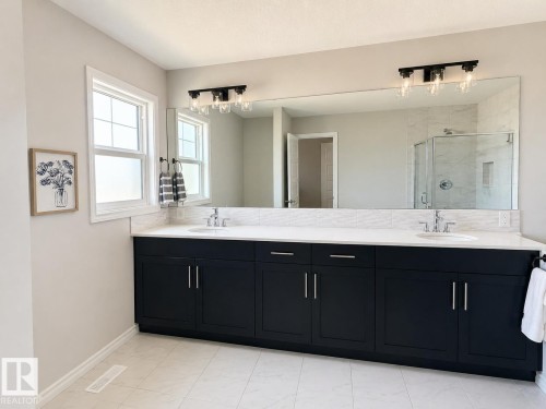 Double vanity with dark cabinetry, white countertops, and dual undermount sinks - 1327 20 Nw, Edmonton, AB - Indoor Photo Showing Bathroom