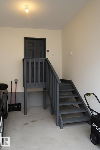 Interior garage access featuring a dark gray painted wooden staircase and landing, leading to a four-panel door - 1327 20 Nw, Edmonton, AB - Indoor Photo Showing Other Room