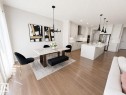 Open-concept living space featuring wood-finish flooring, a contemporary kitchen with white cabinetry and an expansive island, and a dining area with a modern chandelier - 1327 20 Nw, Edmonton, AB  - Indoor 