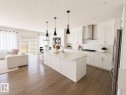 Kitchen featuring a large central island with a sink, white cabinetry, a tile backsplash, stainless steel appliances, and wood-finish flooring - 1327 20 Nw, Edmonton, AB  - Indoor Photo Showing Kitchen With Upgraded Kitchen 