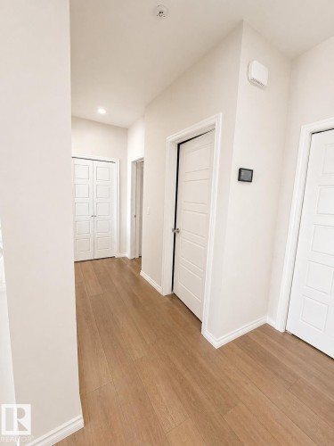 Hallway featuring wood-finish flooring, recessed lighting, white panel doors, and neutral wall paint - 1327 20 Nw, Edmonton, AB - Indoor Photo Showing Other Room
