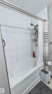 Bathtub with full subway tile surround, integrated shower head, and double shower rod - 