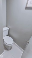 Powder room featuring light gray walls, white baseboards, and light-colored tile flooring - 