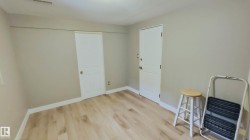 Neutral-toned interior room featuring wood-finish flooring, white baseboards, and two white panel doors - 