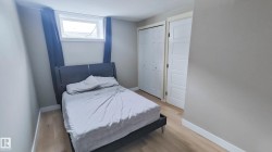 Room featuring light-toned wood-finish flooring, neutral wall paint, and a window with dark drapes - 